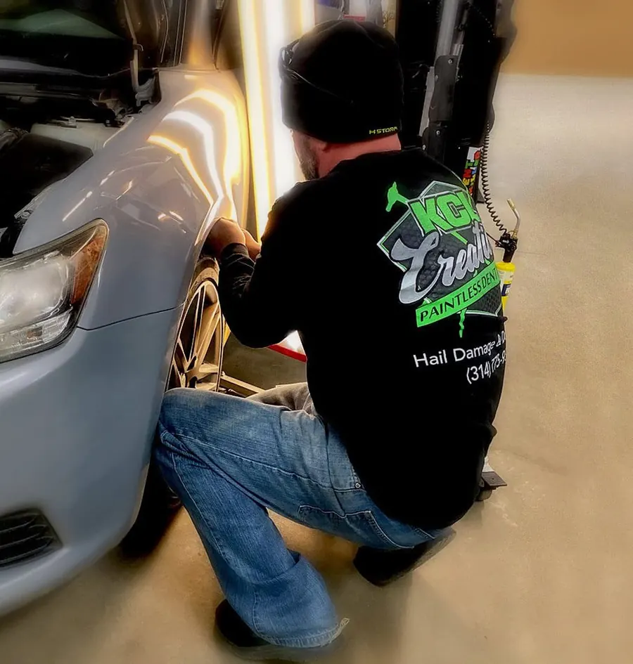 KCL Creations technician using a PDR light board to find dents on a silver car