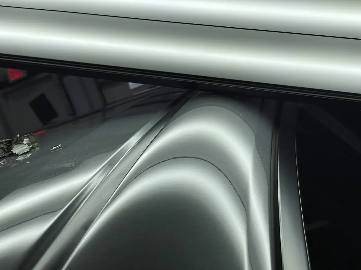 Large dent on a roof rail showing distorted reflection lines