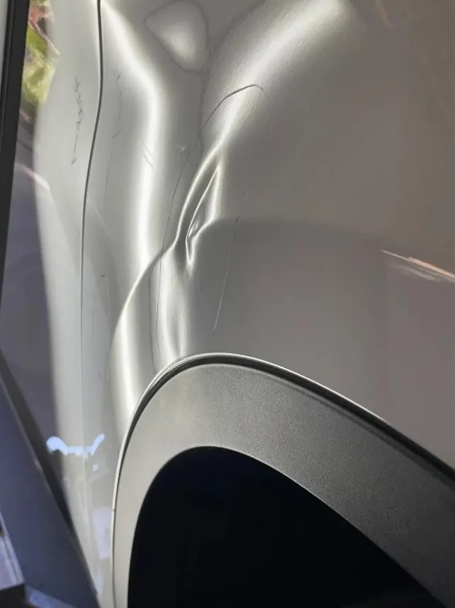 Sharp door dent reflected in the PDR light lines before repair