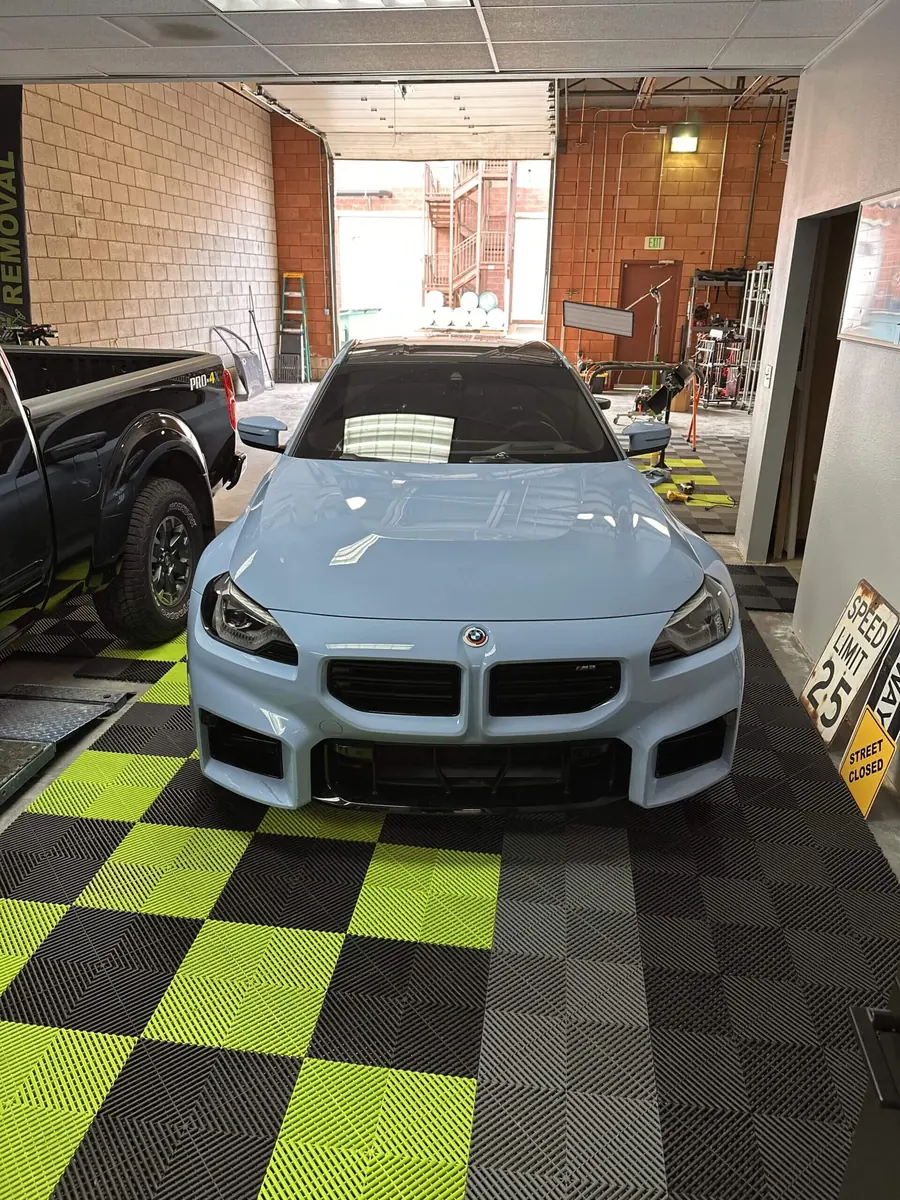 BMW M2 on KCL Creations' green and black shop floor in Loveland after paintless dent repair
