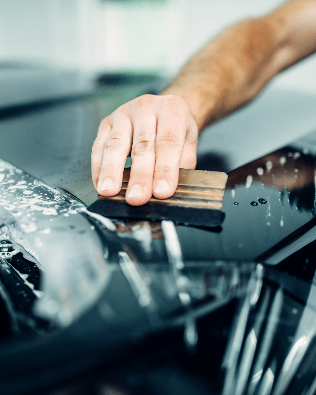 Technician carefully removing paint protection film from a car without damaging the paint at KCL Creations in Fort Collins, CO